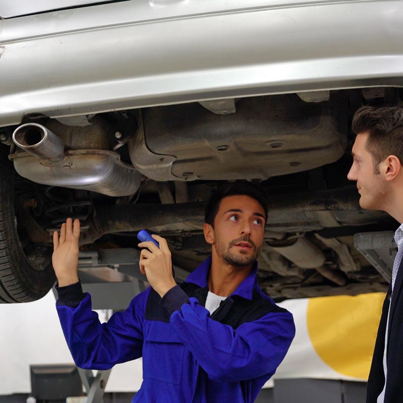auto repair technician showing customer car underbody